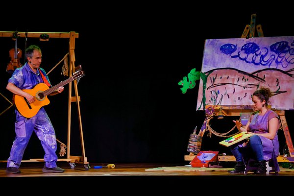 Imagen de fondo negro,  en el centro 2 cuerpos (Javier y Diego), uno de ellos en silla de ruedas, ambos de pantalones rosados, torso y pies desnudos. Están enfrentados uno sentado arriba de otro, abrazados, a un instante de besarse en la boca FVA00518.jpg